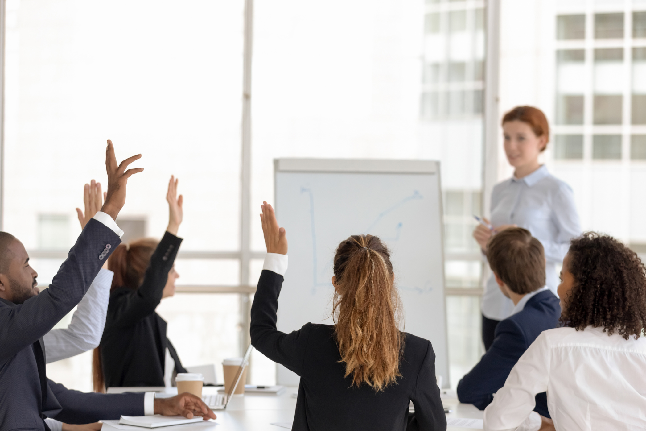 Employees raise hands answering questions at office training